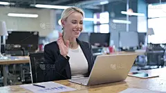 愉快的女商人在办公室用笔记本电脑视频聊天
