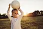 Little soccer playerCute little boy holding a soccer ball standing on a wast grass field at summer