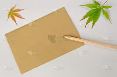 空白的棕色手工纸，问候文字，一支铅笔和两片秋天的叶子在白色的背景。本空间