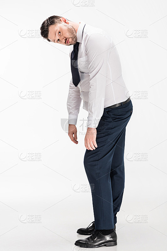 穿紧身正装的超重男子看着镜头，弯腰看白色