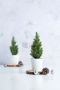 圣诞树与松果，装饰圣诞球的原木在白色的桌子和大理石瓷砖墙的背景。简洁简约的风格。假日静物以空间增添文