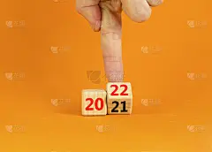 2022年新年快乐的象征。商人变成了一个立方体，象征着从2021年到2022年的变化。美丽的橙色背景