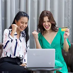 一个穿着绿色衣服的年轻女子和她的朋友一起在客厅度过假期。在网上买到好东西后，两人都举起了拳头，开心地