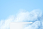Blue background with a product podium surrounded by blue clouds. Free Vector