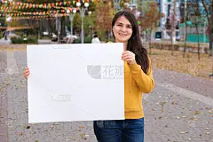 一个黑发的女人微笑着，手里拿着一张空白的白纸，用来写题词和文字