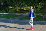 年轻女子运动员走在公园的人行道上