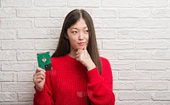 年轻的中国女子抱着硬着脸越过砖墙严肃地思考着问题，非常困惑的想法