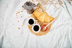 早上好。两杯咖啡配羊角面包和果酱。从上面的白色床单早餐。顶部视图。平躺。复制空间。浪漫早餐.