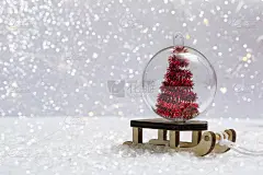 在雪地上——一个雪橇和一个圣诞球在圣诞树上，背景是散景灯。垂直图