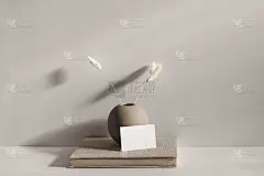 现代文具静物场景。米色球形花瓶，有干燥的拉格鲁斯草。桌面上的背景阳光。空白的名片模型倚在旧书上。香槟