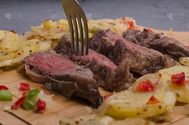 阿根廷牛肉片配土豆，青椒，红椒放在木桌上。