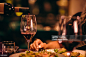 Close-up of sommelier serving red wine at fine dining restaurant