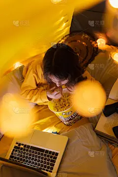 11岁的小女孩在客厅里自制的帐篷下使用笔记本电脑，吃着爆米花。