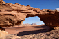 This may contain: an arch shaped rock formation in the desert