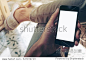 Mockup image of hand holding black mobile phone with blank white screen on thigh with white canvas shoes at vintage tile floor in cafe , feeling relax