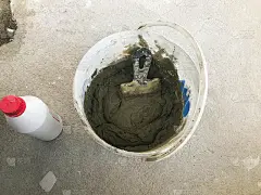 大型白色塑料施工桶，带抹刀和灰泥，瓷砖胶水，水泥，用于修复公寓，房子，找平墙壁和在地板上浇筑平地