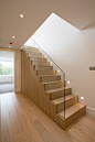 Oak staircase with frameless glass balustrade from hallway to upper level open plan living space.