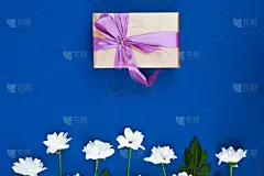 蓝色的桌子上放着礼盒和鲜花。生日、妇女或母亲节贺卡。俯视图