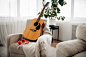 Guitar and headphones on white armchair at home, nobody. acoustic musical instrument and earphones in the room, music lovers concept