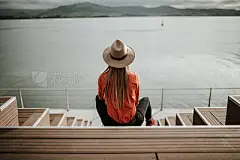 Young woman with hat contemplating a beautiful coastal landscapeRear view of young woman with hat contemplating a beautiful coastal landscape