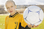 Soccer player holding ball on field - stock photo