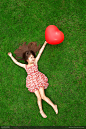 拿着气球躺在绿草地上的小女孩高清图片