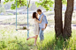 Young kissing couple under big tree with swing