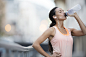 Woman drinking water after exercising on city street by Caia Images on 500px