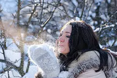 一个戴着手套在雪地上吹气的女人的肖像