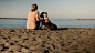 成熟的女人和宠物狗在海滩上放松