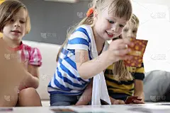 孩子们正坐在桌子旁，一个女孩笑着打着桦树牌。