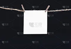 晒衣夹上挂着一张正方形的白纸条，以黑色为背景，以实物为模型