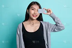年轻的亚洲女人，眼睛上盖着空白卡片。