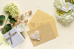 米色桌子上放着一束白色绣球花的礼盒。节日贺卡。信封上写着邀请或祝贺。
