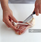 Using kitchen knife to cut around bone of chicken drumstick and freeing it from flesh