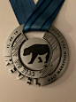 This may contain: a silver medal with a blue ribbon around it