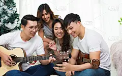 一群亚洲人或朋友在家里的客厅里欢聚一堂，唱歌、弹吉他、跳舞，充满快乐和乐趣。生活方式的概念。