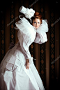 美丽的时装模特高雅的白色礼服和优雅的帽子。复古的风格。艺术项目