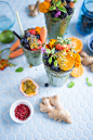 Fruit smoothies in glasses topped with pieces of fruit and marigold flowers