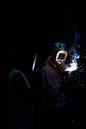 Two people weld in the dark in Nejapa