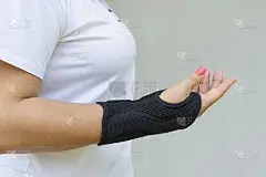 黑色腕托或束身衣戴在女性手上，用于治疗腕管综合征或正中神经压迫、手麻木