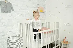 可爱活泼的小女孩躺在育婴室的摇篮里