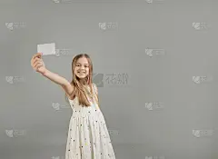 一个穿着夏装的小女孩拿着一张名片，名片上的文字在一臂之遥的灰色背景上