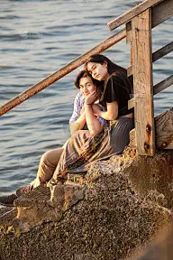 一对年轻的混血夫妇坐在水边的台阶上