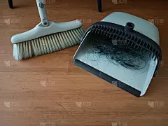 用畚箕上的扫帚扫灰尘，家政概念。