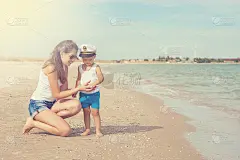 快乐美丽的母亲和儿子享受海滩时光
