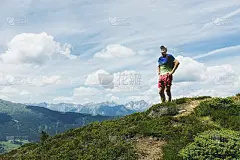 一个人站在风景和山峰的山顶上，双手翘臀仰望蓝天，强壮，孤独，休息。