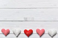 白色的背景上躺着三颗彩色的针织心。