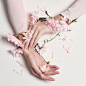 Fashion art portrait woman in summer dress and flowers in her hand with a bright contrasting makeup. Creative beauty photo girls sitting at table on a contrasting pink background with colored shadows