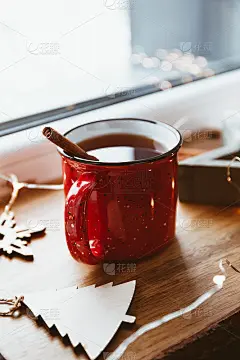 红色杯子里的肉桂红茶，点缀着冬日的装饰和灯光。舒适的冬季静物生活。